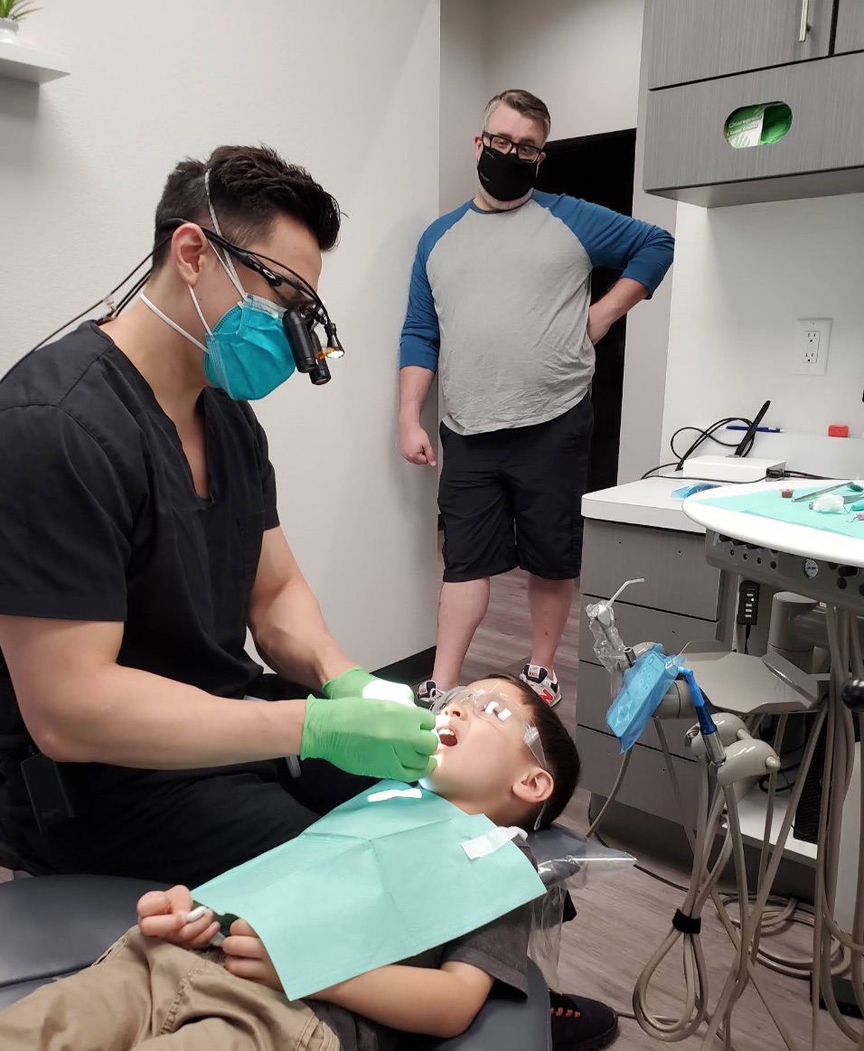 Dr. Kevin Chuang treating a young patient with a parent alongside